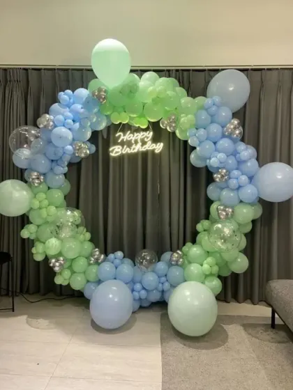 A cool-toned balloon ring in shades of green and blue with a neon sign.