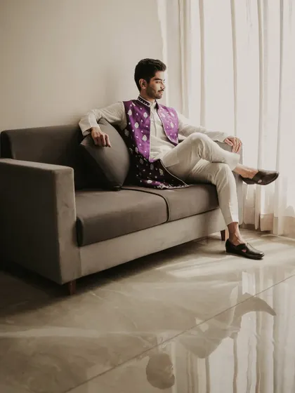 A relaxed and stylish portrait of the groom before the festivities. The natural light from the window and his confident pose create a calm yet dapper image.