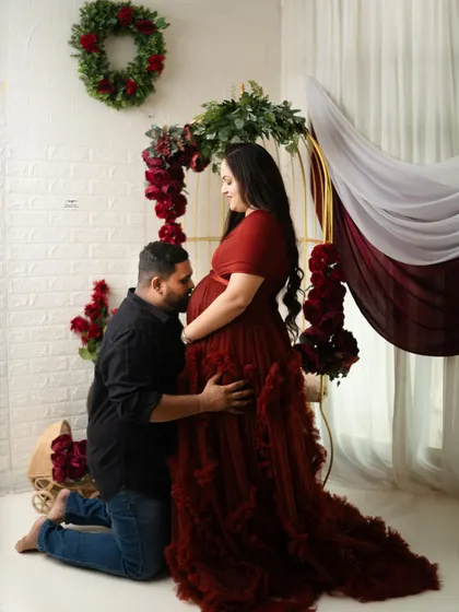 A classic and heartfelt maternity pose. The father-to-be kneels to kiss the baby bump, a gesture filled with love and anticipation.