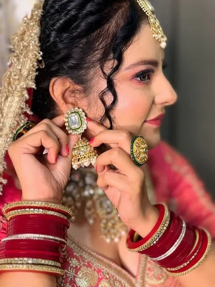 A detailed shot focusing on the bridal jewellery and the classic red bangles (chooda), complementing the embroidered blouse of the lehenga.