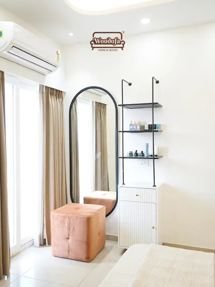 A minimalist dressing corner in the bedroom. The open shelving and oval mirror are simple yet chic, and the burnt orange pouf adds a pop of color and texture.