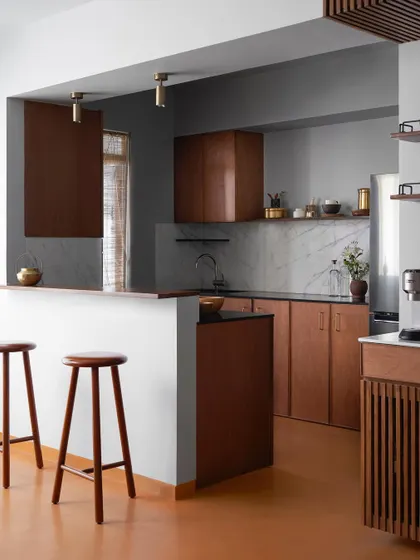 A wide view of the kitchen, showing the custom wood cabinetry, breakfast counter, and bar area. I design kitchens to be the hardworking heart of the home, with durable materials and smart layouts.