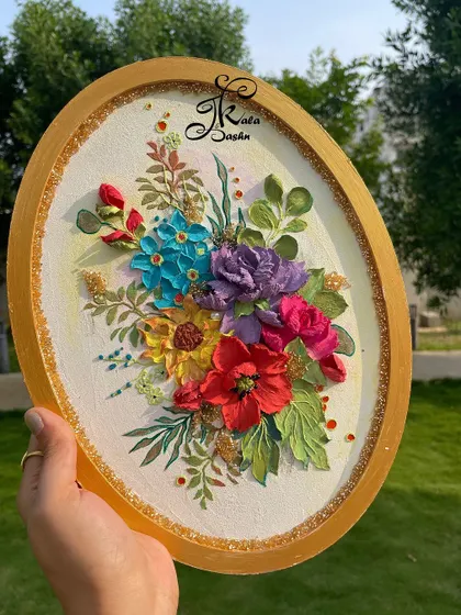 Holding the oval floral panel to showcase its bright colors and golden frame.