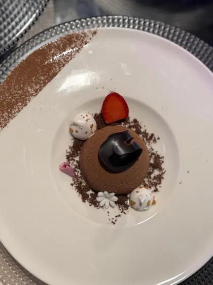 A decadent chocolate sphere dessert, dusted with cocoa and topped with meringue kisses. This dish is a perfect example of how we play with shapes, textures, and flavours to create a memorable finale.