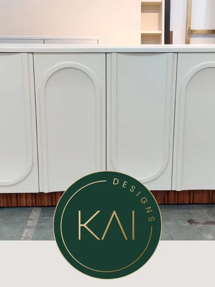 A white four-door cabinet with inset arched panels and a contrasting wood base. This piece is shown in our workshop, highlighting its clean, architectural design.