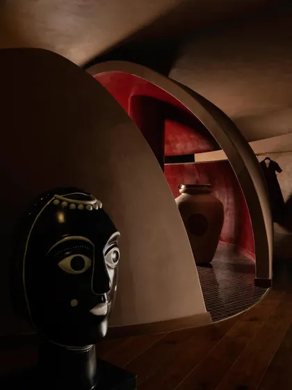 A detail shot capturing the dialogue between art and architecture at the House of Masaba. The signature tribal bust is juxtaposed with a pod-like enclosure, its red interior hinting at a private, sacred space within the store.