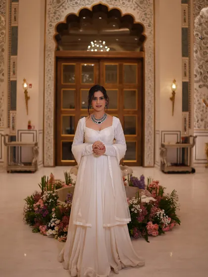 A full-length shot of the white lehenga in a grand lobby, showcasing its elegant silhouette and my poised presence.