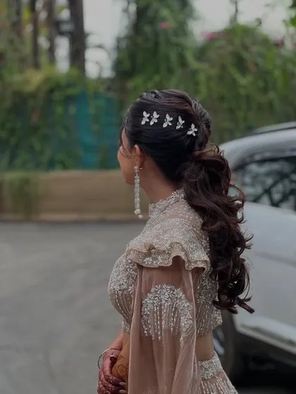 A detailed shot of the elegant ponytail hairstyle I created for bride Simran's Sangeet, adorned with delicate floral pins.