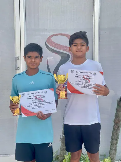 Yashas and his doubles partner posing with their trophies after a successful tournament, showcasing their teamwork and skill.