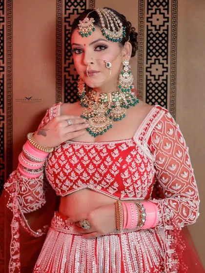 A graceful pose where the bride's hand rests on her chest, highlighting both her jewellery and the delicate embroidery on her blouse.