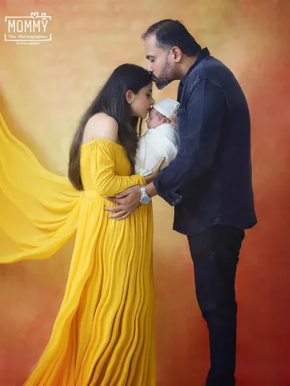 A kiss of love for their new baby. This tender moment between new parents, both kissing their newborn's head, is what family photography is all about.