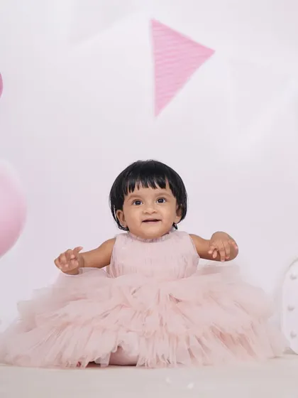 A delightful portrait of a baby girl in a fluffy pink dress, surrounded by birthday decorations in the studio. I focus on capturing these precious, fleeting expressions of wonder.