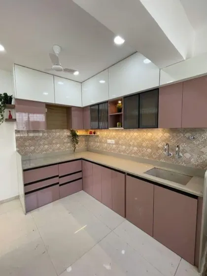 A lovely L-shaped kitchen in a dusty pink laminate finish. The patterned backsplash and black profile handles add a modern, graphic touch to the soft color palette.