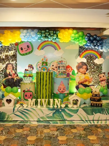 This grand Cocomelon stage was created for Mivin's first birthday. It features a huge backdrop with characters and rainbows, custom cutouts, themed flooring, and a vibrant balloon arch, making it a true Cocomelon wonderland.