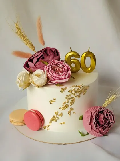 A lovely floral cake to celebrate a 60th birthday. This design is adorned with crepe paper flowers, macarons, and a touch of gold leaf for a sophisticated finish.
