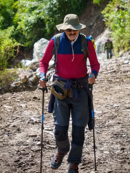 Age is no barrier to adventure. A senior trekker, fully equipped with poles, confidently makes his way along the trail during the first day of our Annapurna Base Camp trek.