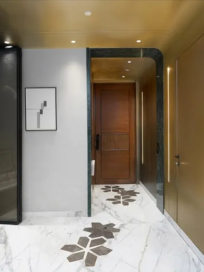 This entryway in a New Delhi residence sets a refined tone with warm brass paneling, custom marble flooring, and integrated lighting. We seamlessly blended a modern aesthetic with a dedicated pooja alcove, showing our commitment to integrating our client's spiritual and cultural needs.