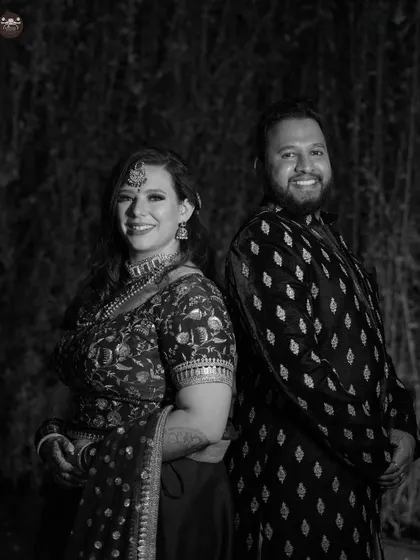 A happy black and white portrait of a couple standing back to back. Their smiles and relaxed poses create a fun and engaging photo from their wedding celebration.