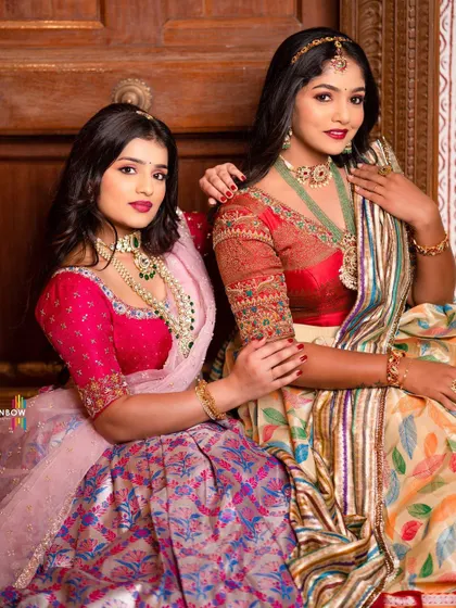 Two models showcasing my collection of silk Langa Voni. The vibrant pink and multi-colored leaf print outfits highlight the variety available for rent.
