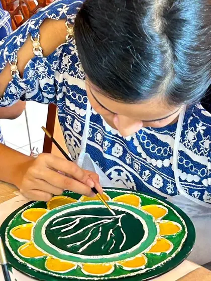 A close-up of a participant painting the details on her Lippan art piece.