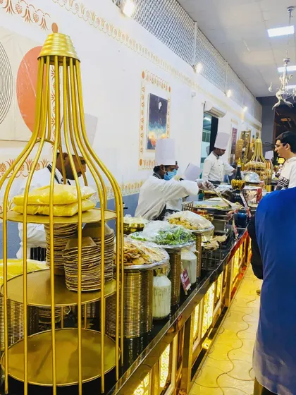 A wide view of a long buffet line with my chefs serving guests. The setup is designed for efficient flow and an elegant presentation, ensuring a pleasant experience for everyone.