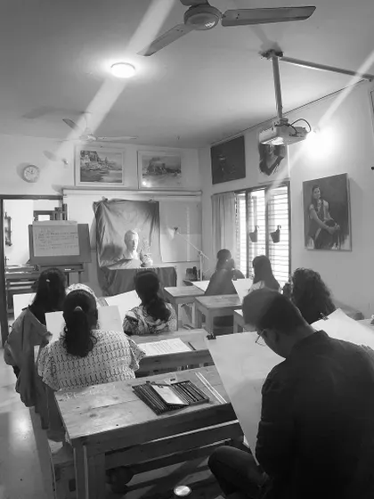 A black and white shot of an exam session, highlighting the timeless nature of artistic practice. Students are focused on a live model study, a classical method for honing observational skills.