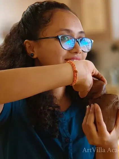 A student holds her clay, planning her design. Our workshops encourage both guided learning and individual creativity.