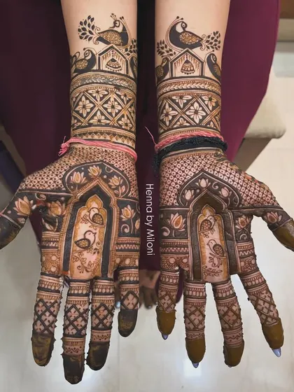 This bridal design features a flock of peacocks and swans, with delicate lotus patterns on the palm and intricate checkwork on the fingers.