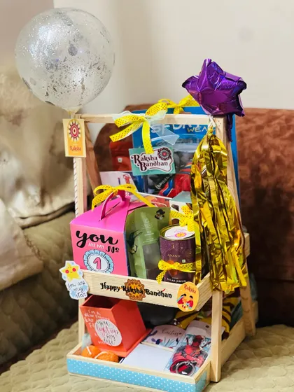 This two-tiered Rakhi hamper is packed with gifts, making it a grand gesture for a beloved sibling.
