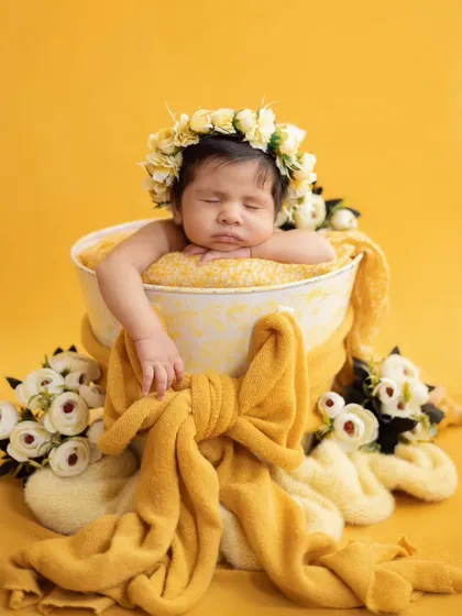 A little ray of sunshine. This bright and cheerful setup with a yellow theme and a floral crown makes for a happy and adorable newborn photo.