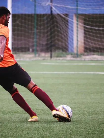 A senior player taking a shot on goal. Our training includes extensive shooting practice to ensure clinical finishing.