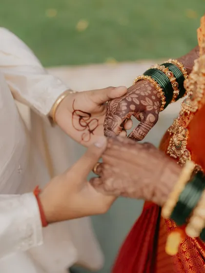 A close-up of the groom's hand with the wedding date written in mehndi, holding the bride's hand.