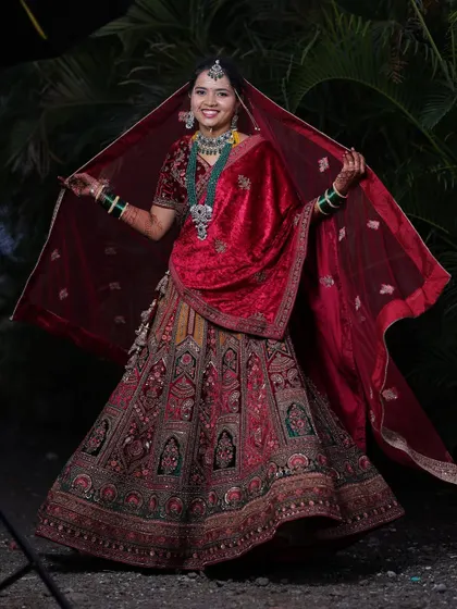 A full view of this gorgeous bride, her red velvet dupatta spread out to showcase the beautiful embroidery of her wedding lehenga.