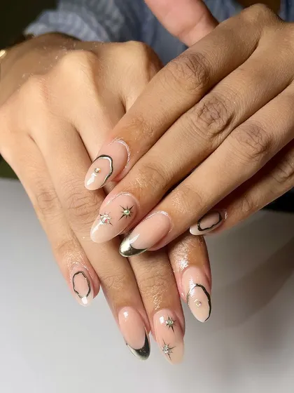 Shine bright with these stunning chrome nails. This set features a mix of gold and black chrome accents, with star details and a stone for extra glam.