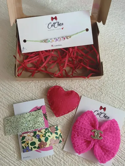 Our Rakhi hamper for sisters includes a beautiful crochet bow, glitter clips, and a felt heart, along with a custom name Rakhi for the brother.