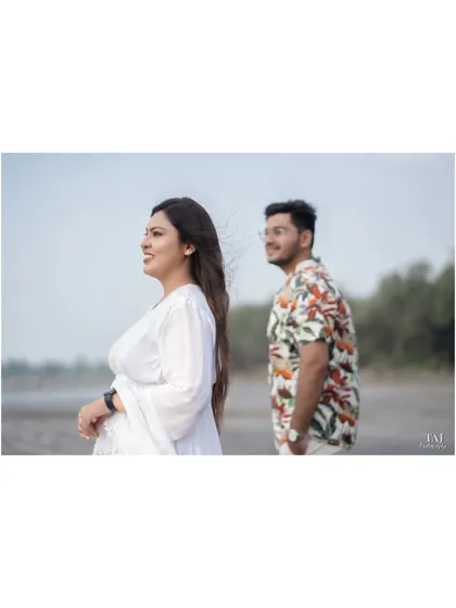 A candid shot of the bride looking out towards the sea, with the wind catching her hair. The groom is slightly out of focus in the background, creating a sense of story and depth.