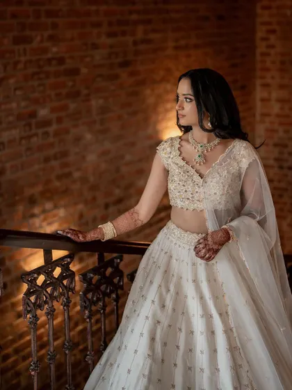 A stunning bride in a white lehenga, exuding grace and elegance. We use creative framing and lighting to capture a variety of beautiful portraits.