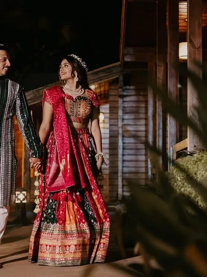 Another angle of the couple's night-time walk, capturing their elegant traditional ensembles in a festive setting.