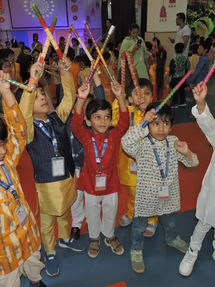 Boys in traditional attire raise their dandiya sticks in the air, full of energy and excitement for the dance.