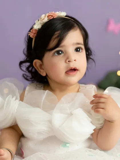 A calm and beautiful portrait taken before the cake smash, highlighting the baby's delicate features and the soft studio lighting.