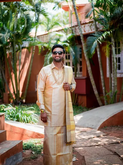 A full-length portrait of the groom in his stylish South Indian attire, looking relaxed and happy.