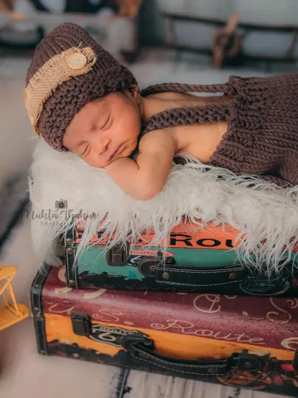 The composition here includes a vintage toy plane and telephone booth, adding more layers to the travel story. The baby remains the serene centerpiece of the adventure.