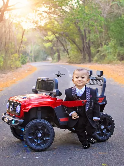 This little gentleman is ready to celebrate his first birthday. Dressed in a sharp suit, he looks so dapper next to his red toy jeep.