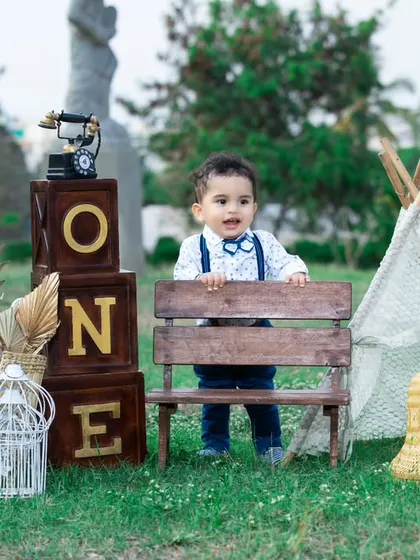 A stylish little gentleman at his first birthday picnic, looking dapper in his bow tie and suspenders.
