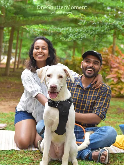 A happy dog makes for a happy family. This couple's joy is infectious as they pose with their handsome white dog during a fun outdoor session.