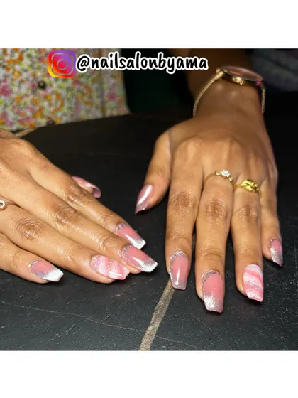 A client showing off her new nails, which feature a combination of pink marble art and a soft glitter fade on the tips.