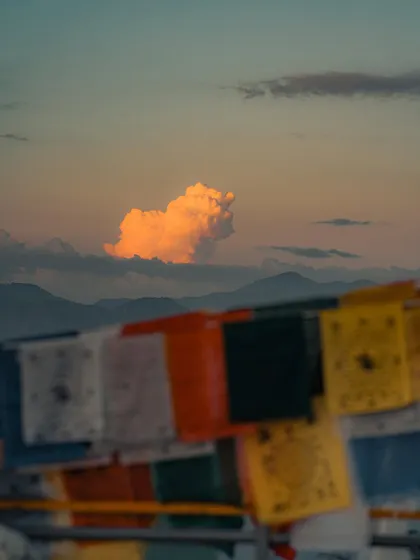 A single orange cloud floating above the mountains, framed by prayer flags. Sometimes the simplest moments in nature are the most beautiful.