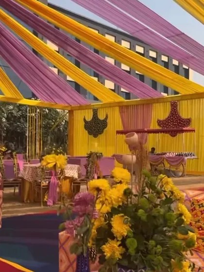 A glimpse of a Haldi setup with yellow and purple tent drapes. The decor includes intricate floral chandeliers, showcasing our attention to detail in every element.