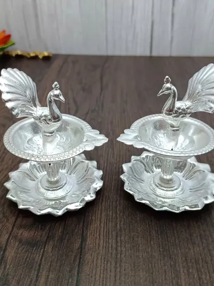 This pair of two-tiered peacock diyas is perfect for creating a layered light effect. Made from German silver, they are both functional and highly decorative.