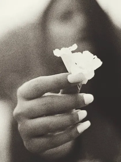 A grainy, black and white version of the flower portrait, giving it a timeless, film-like quality. The focus remains on the hand and the flower, emphasizing the theme of empowerment and the simple, significant details of a moment.
